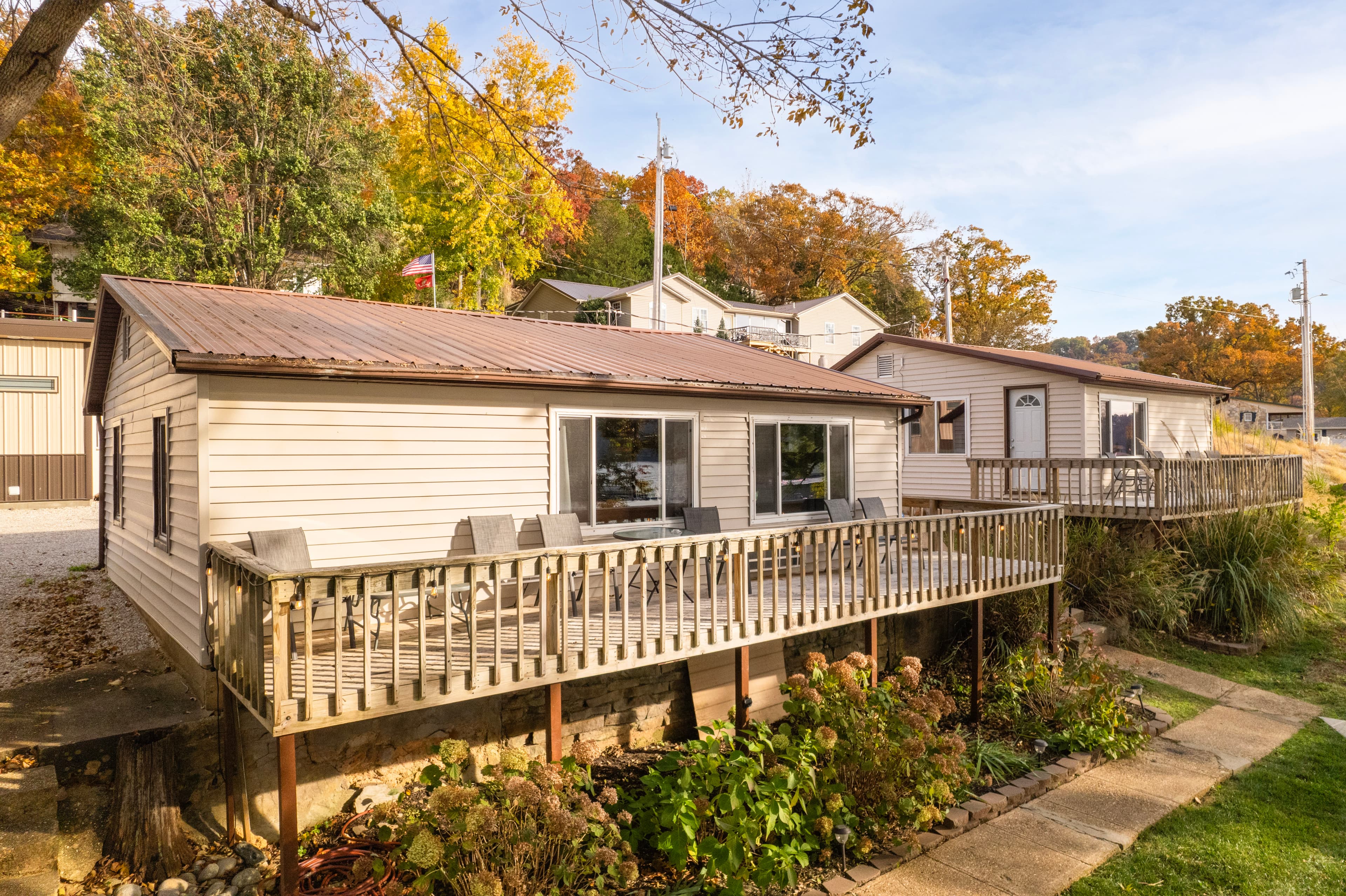 Two houses with decks surrounded by autumn foliage.