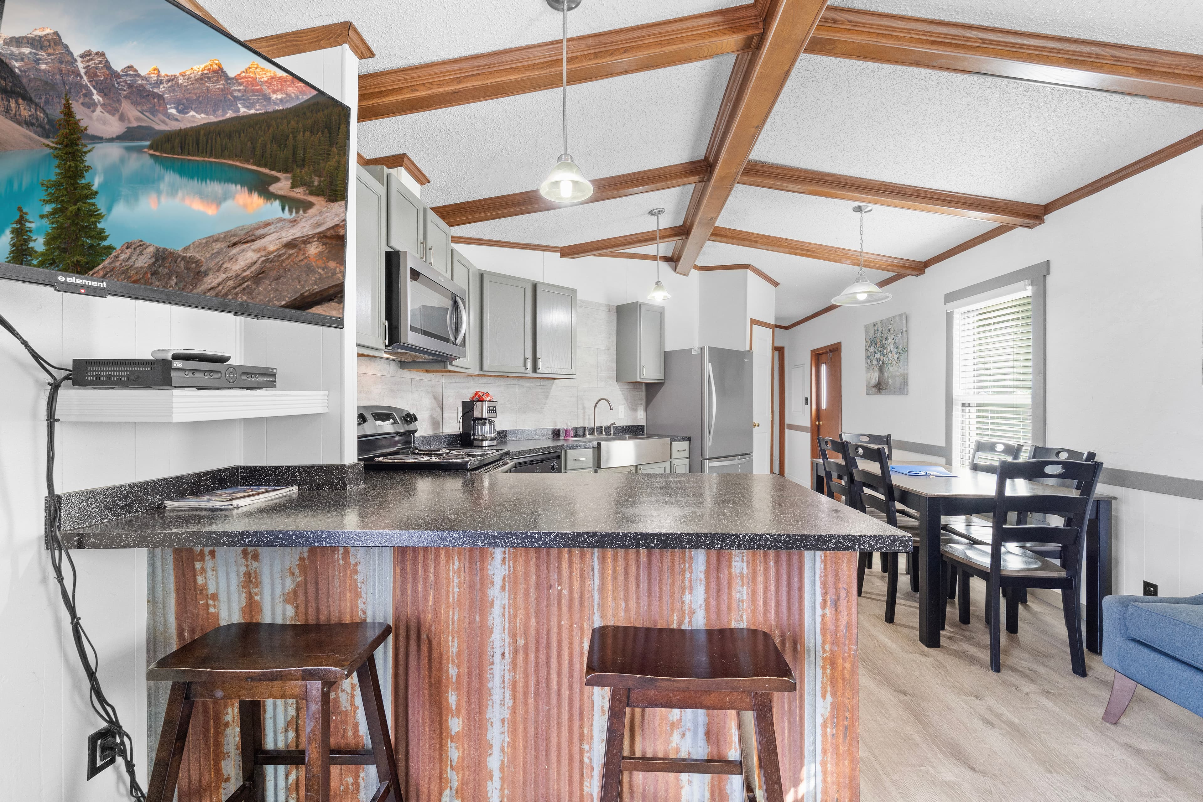 A modern kitchen with a rustic bar, featuring stainless steel appliances and a dining area.