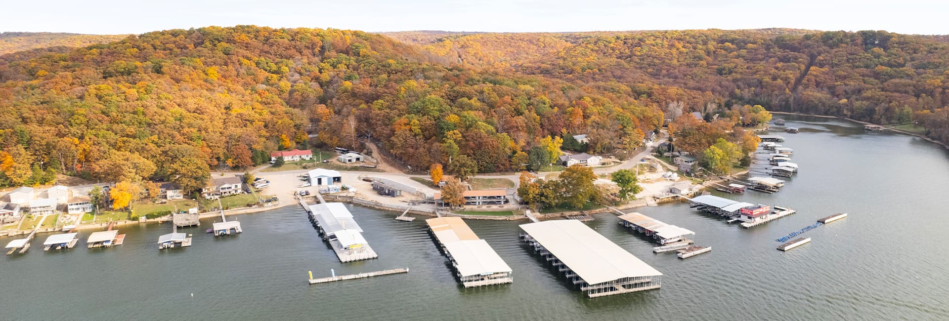 Aerial view of a lakeside marina surrounded by autumn foliage.