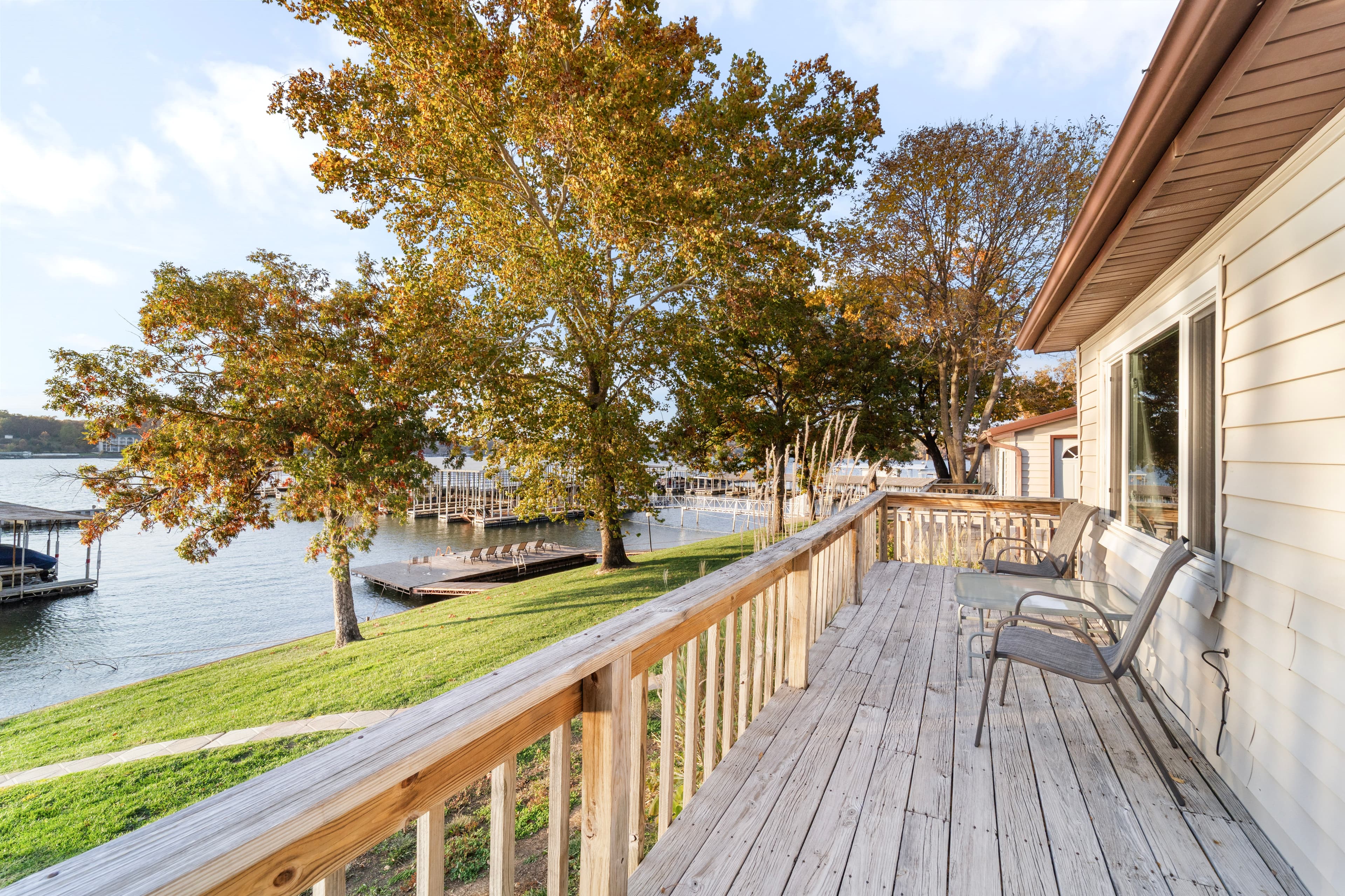 Deck overlooking a tranquil lake surrounded by trees in autumn.