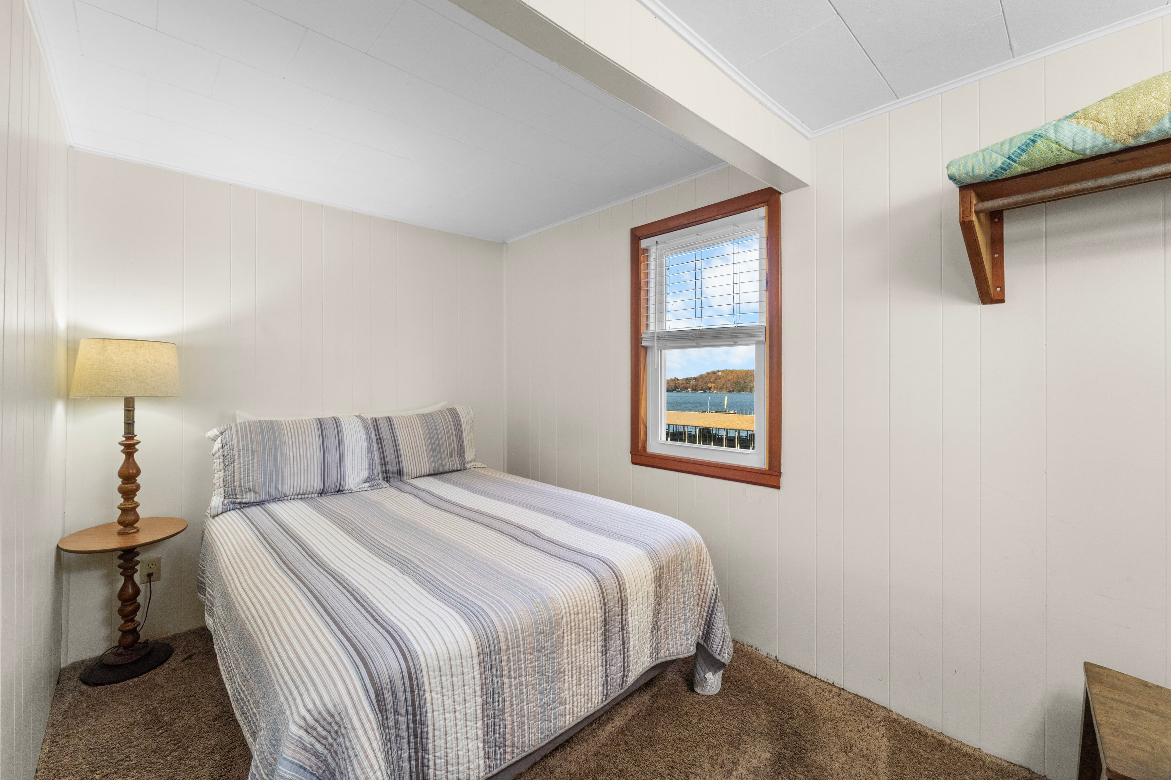 Cozy bedroom with a double bed, lamp, and a window view.