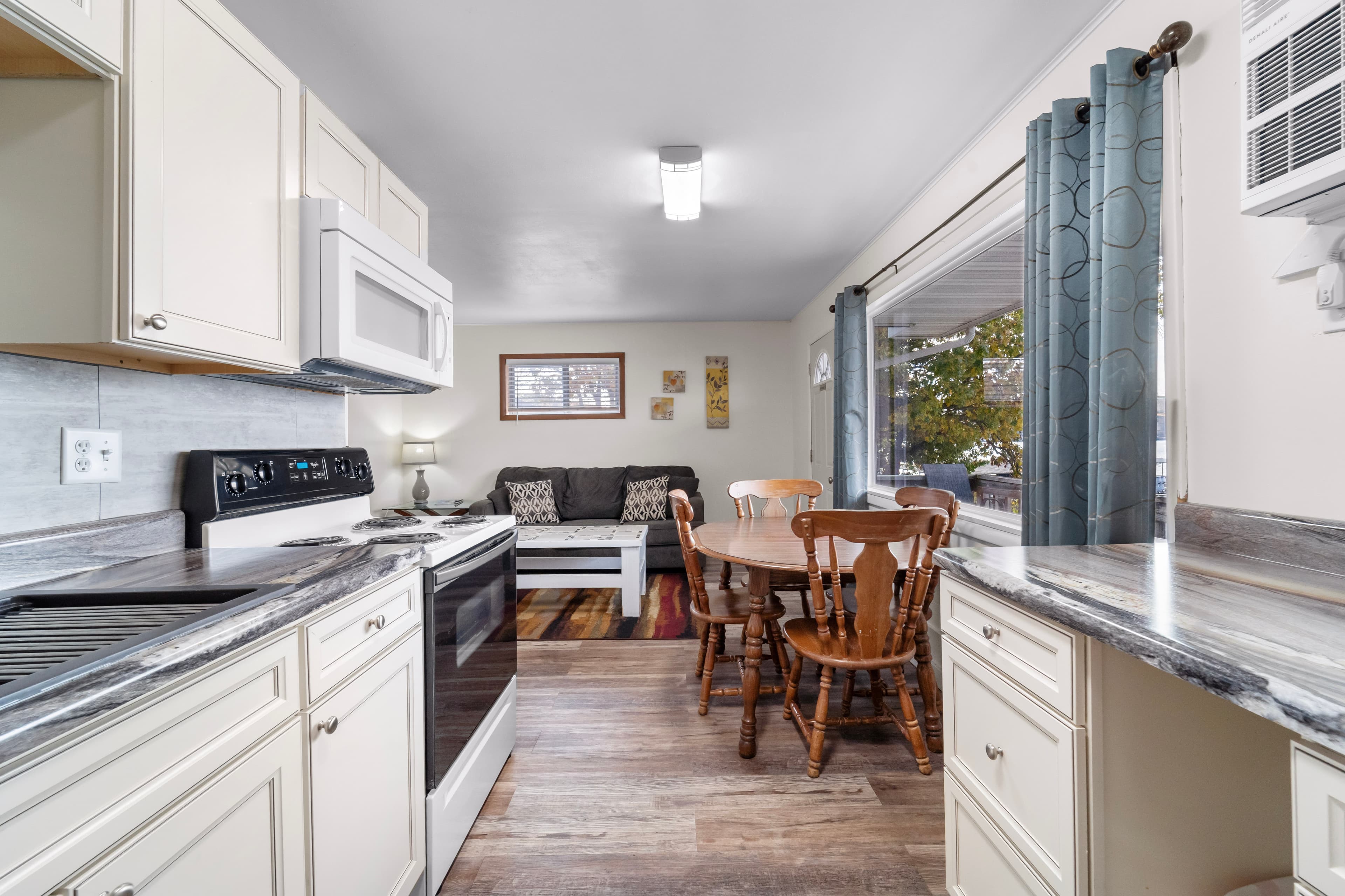 A modern kitchen connects to a cozy living area with seating and natural light.