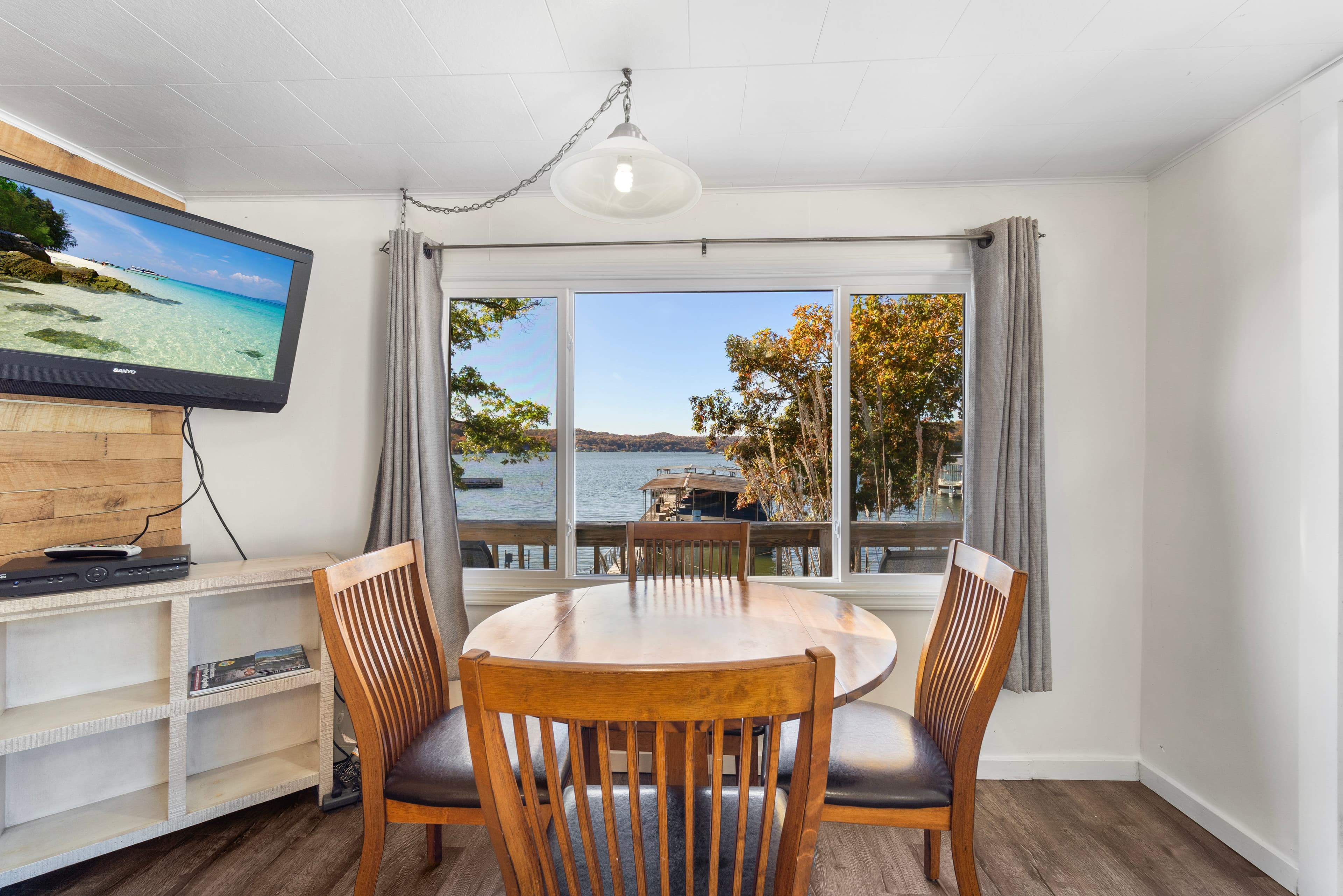 Cozy dining area with a view of a lake and a wall-mounted TV.