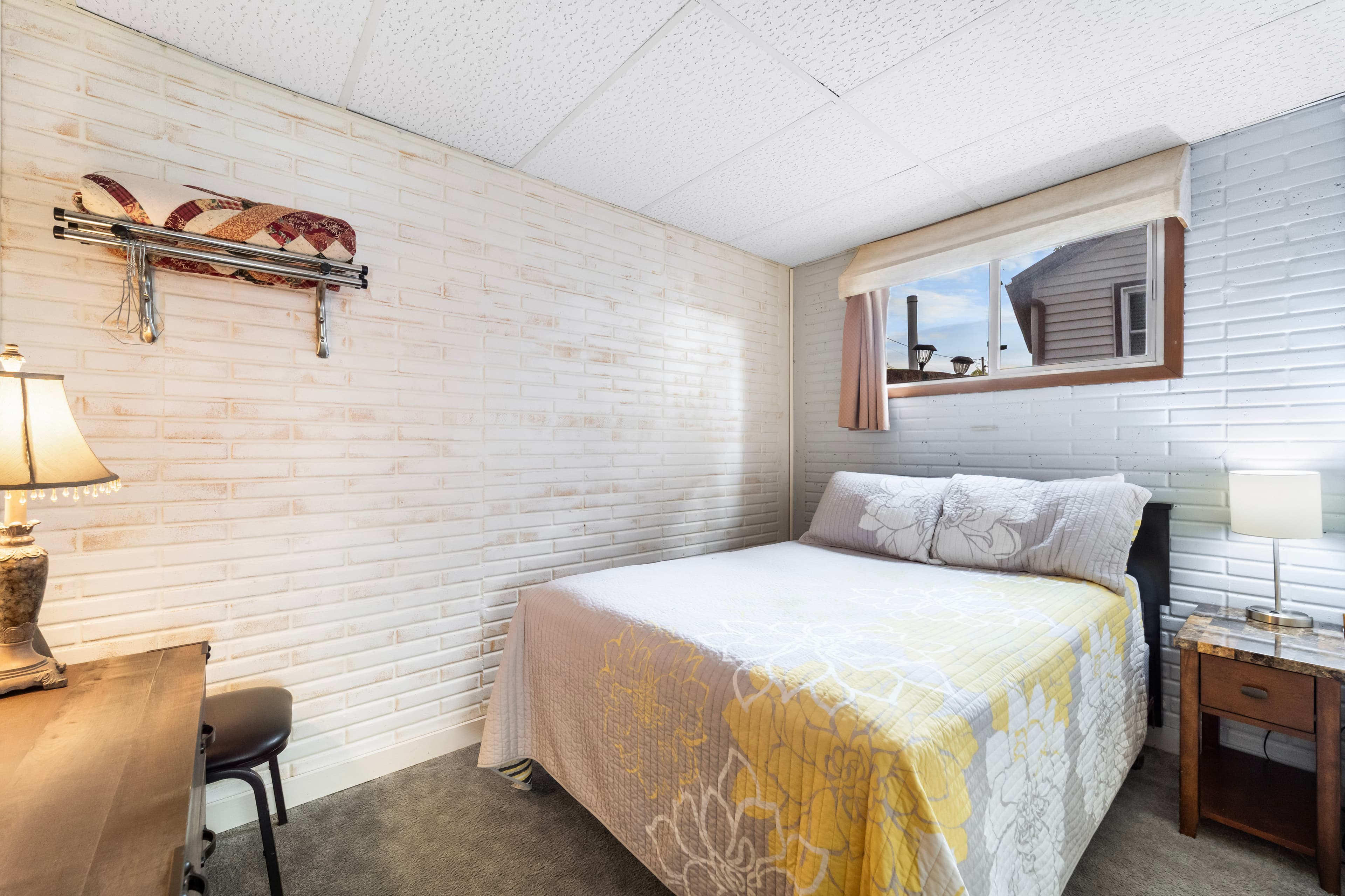 Cozy bedroom with a bed, nightstand, lamp, and a window.