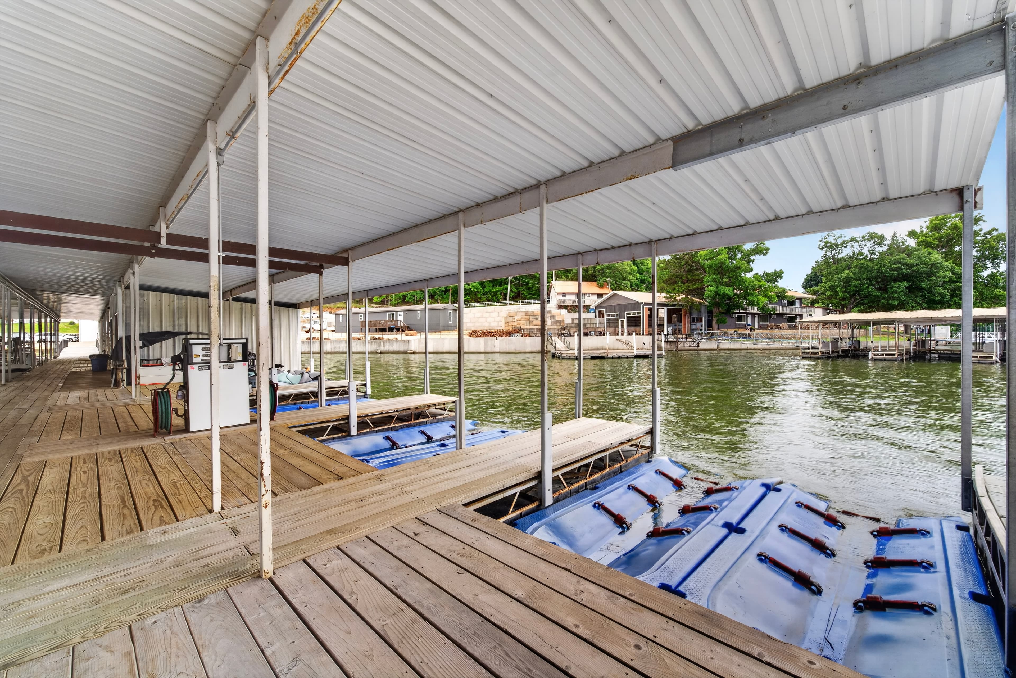 A view of a boat dock with several covered slips on a calm body of water.