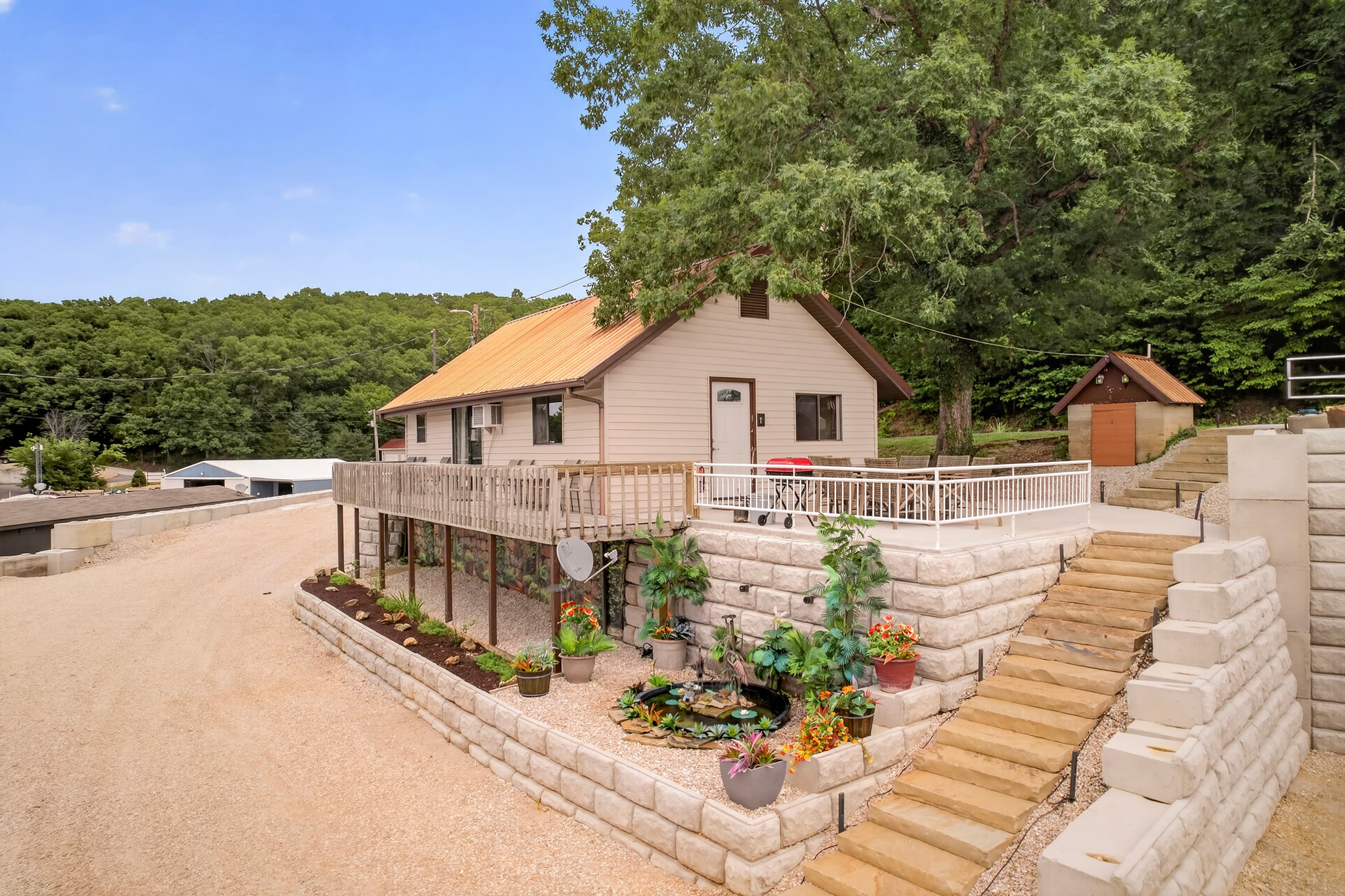 A charming house with a metal roof surrounded by greenery and landscaped gardens.