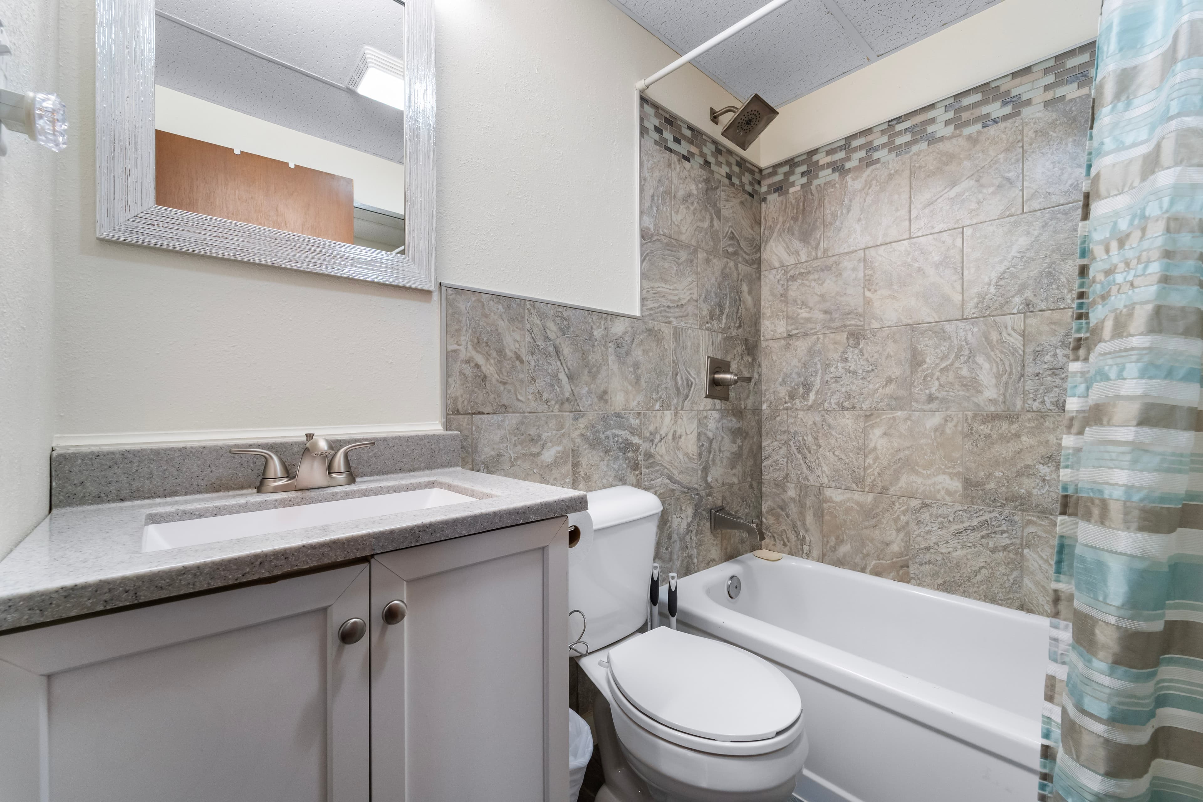 A modern bathroom featuring a bathtub, shower, and a vanity with a mirror.