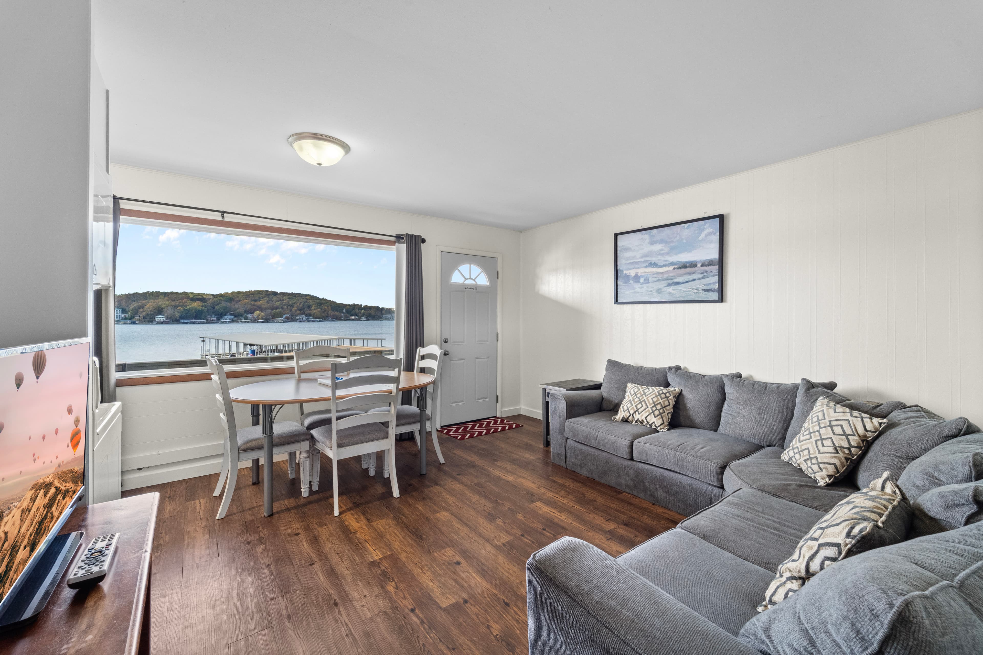 Cozy living area with a view of the water, featuring a gray sofa and dining table.