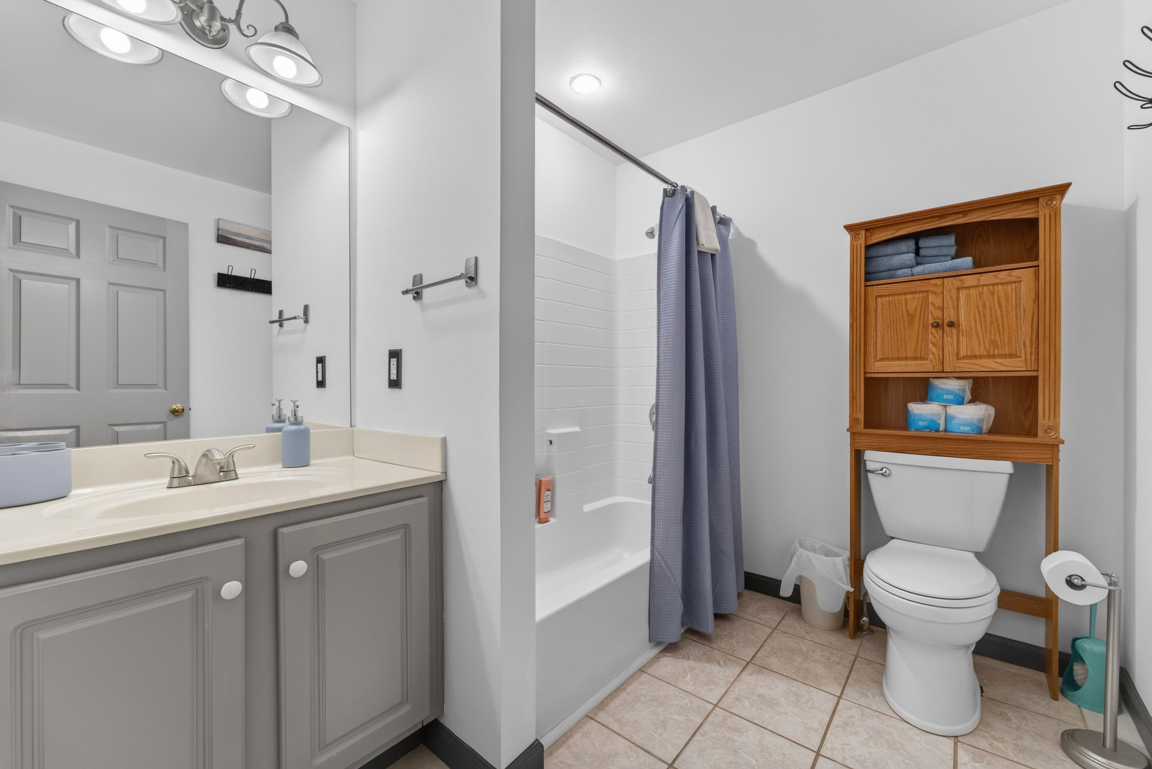A clean and modern bathroom featuring a shower, toilet, and wooden storage unit.