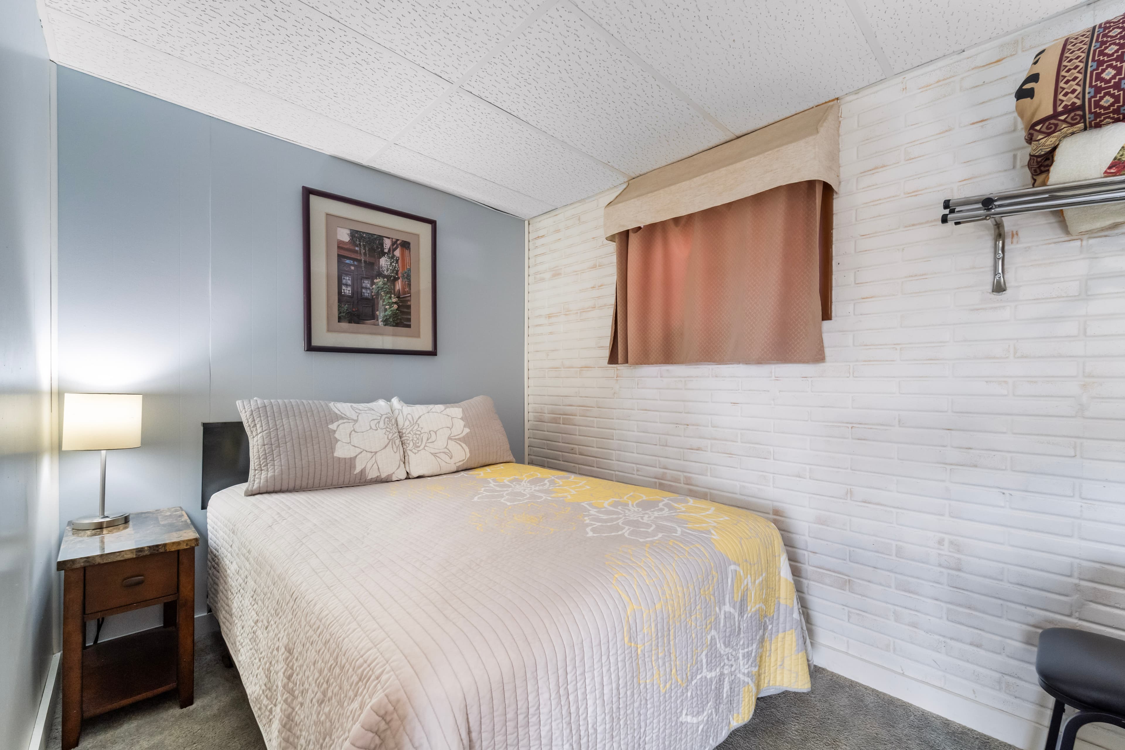 A cozy bedroom featuring a double bed, bedside lamp, and artwork on the wall.